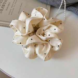 Detail of cream silk scrunchie with black polka dots and delicate lace trim accents