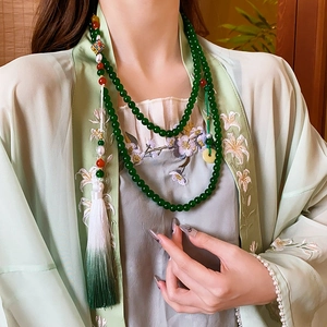 Detail of beaded flower necklace with green pearls and elegant gradient silk tassel