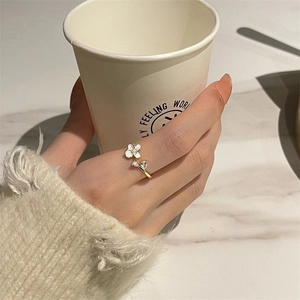Détail d'une bague fleur dorée ajustable avec pétales blancs et zircons brillants