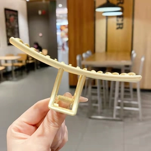Détail d'une grande pince à cheveux en métal doré mat avec ressort robuste et dents