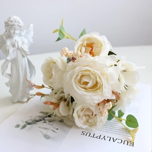Close-up of white silk rose bouquet with green leaves and berries for home decor
