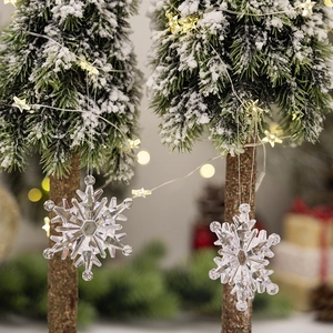 Close-up of clear acrylic snowflake ornaments on a miniature Christmas tree with warm lights