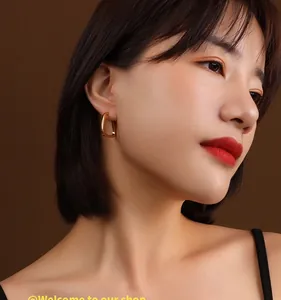 Close-up of model wearing gold geometric U-shaped hoop earrings in minimalist 18K style