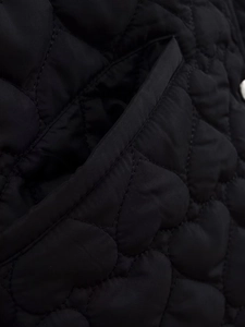 Close-up of black quilted jacket featuring heart-shaped stitching and pocket detail