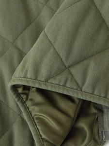 Macro shot of army green diamond quilted jacket fabric with detailed stitching and lining
