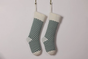 Detail showing two green and white striped knitted Christmas stockings hanging on hooks