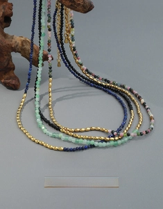 Détail de colliers bohèmes en pierres naturelles avec lapis et turquoise sur bois