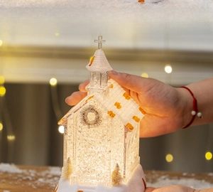 Close-up of a frosted Christmas church lantern with LED light and gold glitter accents