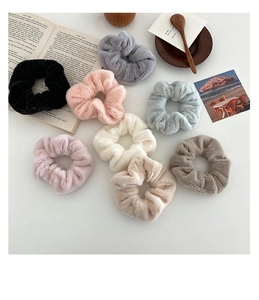 Close-up of soft plush scrunchies in multiple colors including black and beige