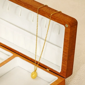 Minimalist stainless steel golden necklace with oval pendant in a luxury wooden box