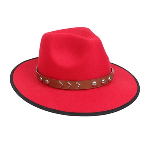 Detail of red fedora hat featuring black brim edging and brown studded leather band