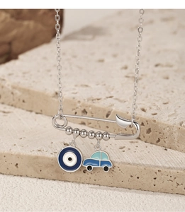Detail of silver safety pin necklace with blue evil eye and car charms on stone