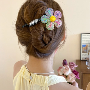 Détail d'une pince à cheveux fleur tissée colorée avec strass en cœur sur une coiffure