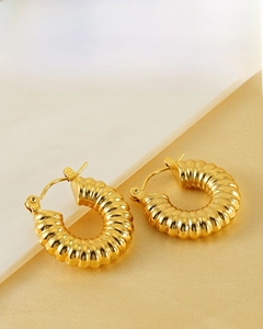 Detailed macro view of 18k gold plated ribbed croissant earrings on silk background