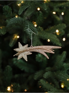 Close-up of golden glitter star hanging on a Christmas tree with warm festive lighting