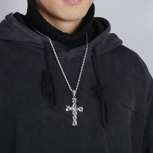 Close-up of a vintage silver twist cross pendant necklace on a black hoodie model