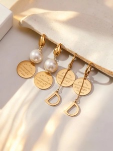 Détail de boucles d'oreilles vintage dorées avec perle et pendentif à pampille lettre D