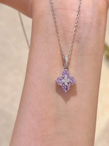 Detail of a sparkling purple zircon clover pendant on a delicate silver chain necklace