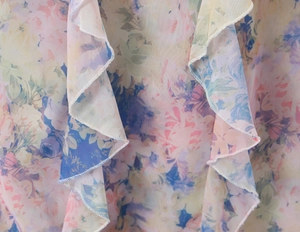 Macro detail of floral chiffon fabric with delicate ruffled edges and precise stitching