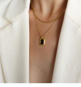 Detail of layered gold titanium necklace with a minimalist black rectangular pendant