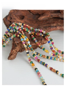 Detail of colorful faceted beads and golden hexagon spacers on a wooden prop