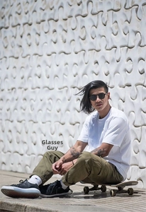 Outdoor streetstyle foto van een retro ronde zwarte zonnebril met een skateboard en kleding