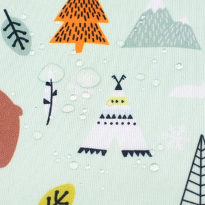Close-up of waterproof mint green fabric with forest prints showing water droplets