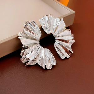 Detailed view of silver petal earrings with pleated metallic texture on a leather base