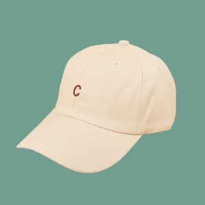 Close-up of red 'C' letter embroidery on a minimalist beige cotton twill baseball cap