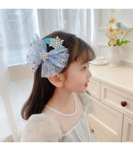 Detail of blue tulle bow hair clip with snowflake patterns on young girl's hair