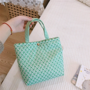 Detail of green floral canvas bag featuring a golden snap button and thick cotton fabric