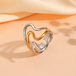 Detail of multi-layer wavy gold and silver mixed metal ring on a beige silk background