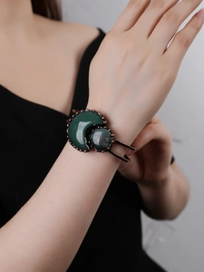 Close-up of vintage bronze cuff with crescent green stone and iridescent labradorite