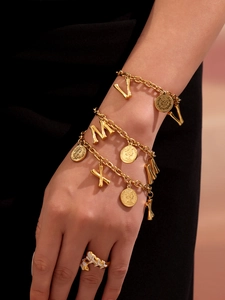 Detailed shot of 18K gold plated coin bracelets and shimmering zircon rings on wrist