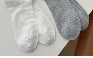 Detailed texture of white and grey ribbed knit cotton socks with bow and bell accents