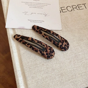 Dettaglio di fermagli per capelli con stampa leopardata su una carta decorativa dai toni caldi
