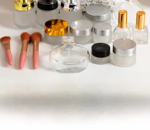 Detail of floral makeup bag with various cosmetic glass bottles and pink makeup brushes