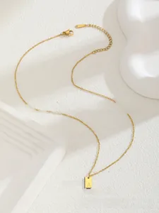Détail du collier en acier inoxydable doré avec un pendentif carré gravé de la lettre A