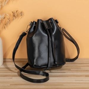 Classic black drawstring bucket bag in glossy PU leather with gold hardware and strap