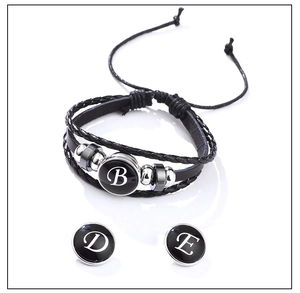Detail of black braided leather bracelet with round letter B, D, and E alphabet charms