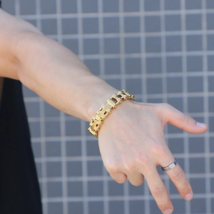 Close-up of a men's gold industrial bicycle chain bracelet and vintage woven ring