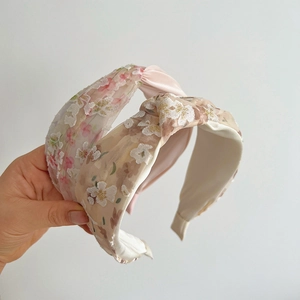 Detailed embroidery flowers on mesh headband with elegant knotted twist design