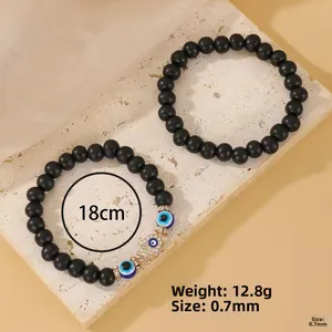 Detail of matte black beaded bracelets with gold Hamsa hand and blue evil eye charm