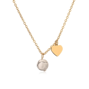 Detail of gold heart pendant and white marble bead necklace with mirror reflection