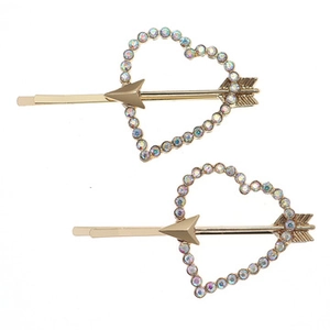 Detail shot of two gold heart hair pins with colorful rhinestones and arrow design