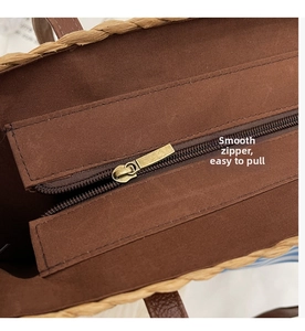 Detail of straw bag featuring a smooth bronze metal zipper and dark brown canvas lining