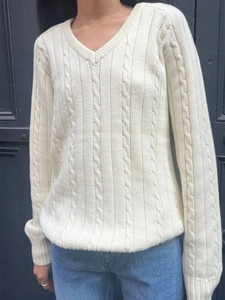 Detailed close-up showing the elegant cable knit pattern on a white V-neck sweater