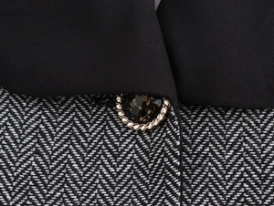 Detail of tweed fabric with contrast black collar and gold braided decorative button