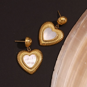 Gros plan de boucles d'oreilles cœur en or 18K avec nacre et texture soleil radieux