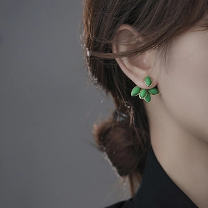Detailed side profile of a vintage green leaf earring on model with golden metal base